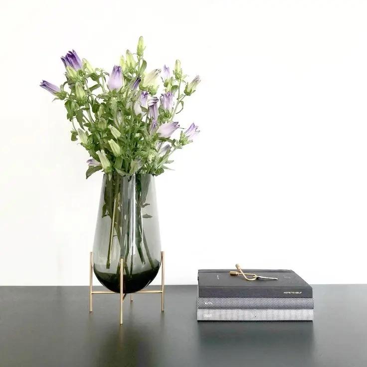 Modern creative dark glass vase with a gold stand.